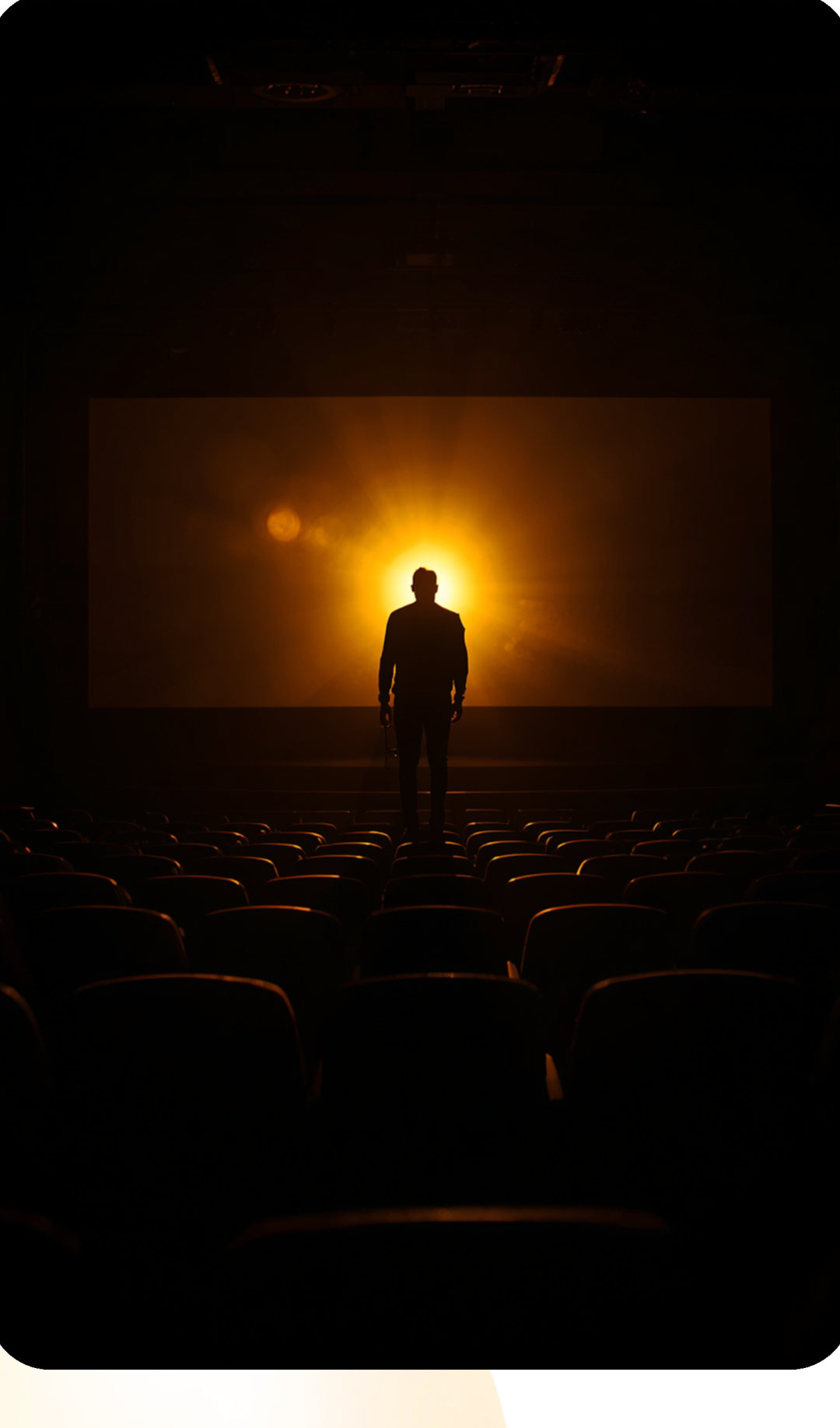 Une personne debout dans une salle de cinéma face à l'écran lumineux